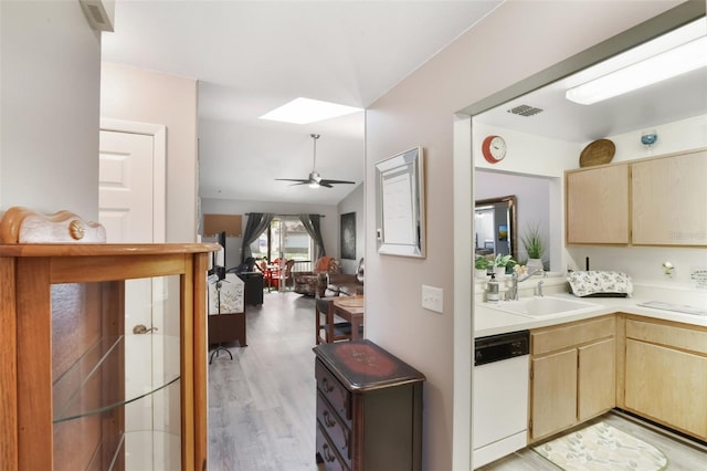 kitchen featuring light brown cabinetry, light wood-style floors, white dishwasher, light countertops, and a sink