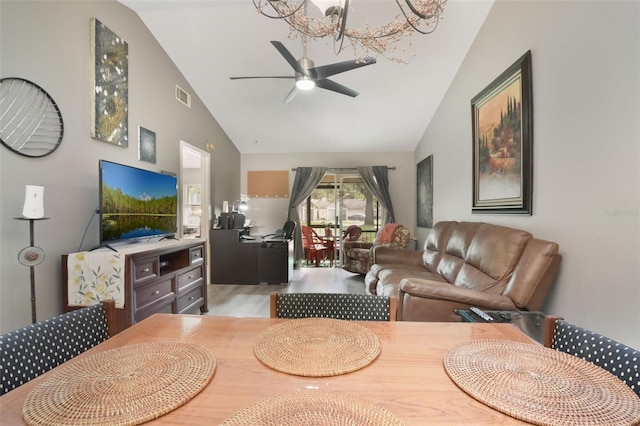 living area with high vaulted ceiling, ceiling fan with notable chandelier, wood finished floors, and visible vents