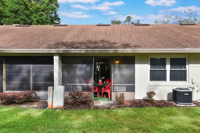 property entrance featuring roof with shingles, central air condition unit, stucco siding, and a yard