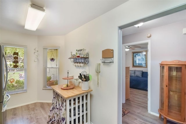 interior space with light wood-style floors, a ceiling fan, and baseboards