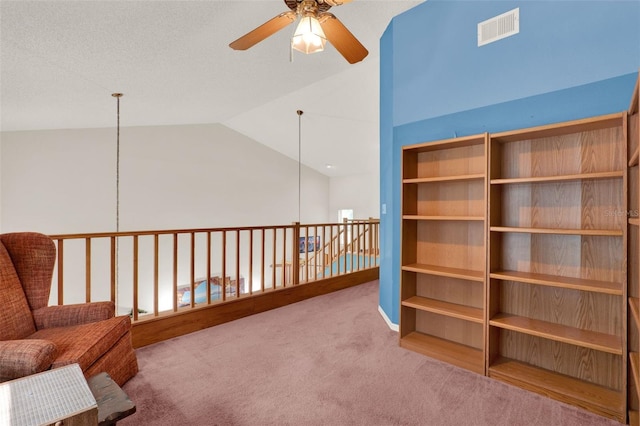 unfurnished room with a ceiling fan, visible vents, vaulted ceiling, and carpet flooring