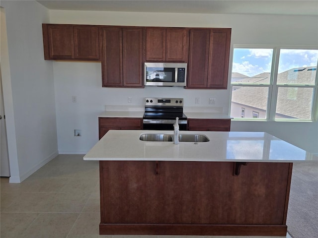 2980 Embark Trl, Saint Cloud, FL 34771 - kitchen with appliances with stainless steel finishes, light countertops, light tile patterned floors, a kitchen island with sink, and a kitchen breakfast bar