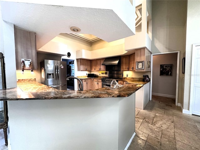 8935 Jonathan Manor Dr, Orlando, FL 32819 - kitchen featuring exhaust hood, a peninsula, stone tile floors, appliances with stainless steel finishes, and baseboards