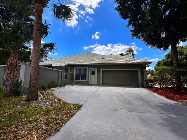 8935 Jonathan Manor Dr, Orlando, FL 32819 - ranch-style home with a garage, stucco siding, concrete driveway, and a tile roof