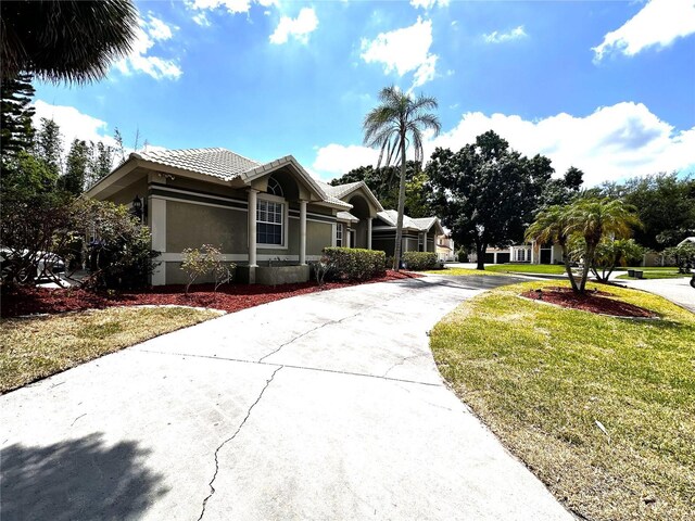 8935 Jonathan Manor Dr, Orlando, FL 32819 - view of front of home with a tiled roof, a front yard, driveway, and stucco siding