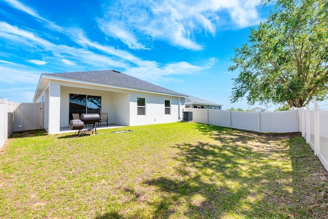 4231 Swan St, Haines City, FL 33844 - back of property featuring roof with shingles, stucco siding, a fenced backyard, central AC, and a lawn