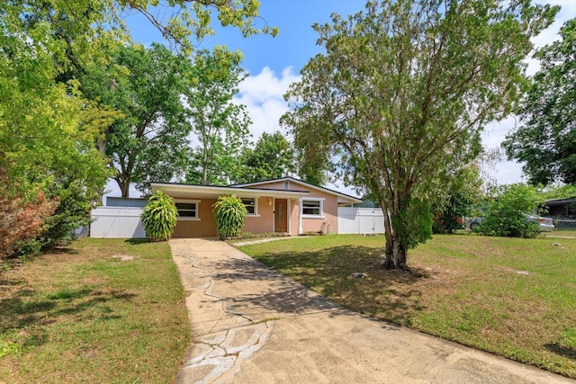 view of front facade featuring stucco siding, a carport, a front yard, fence, and driveway