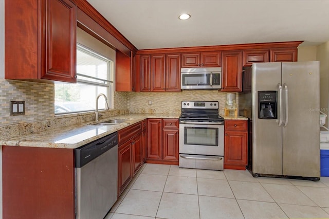 kitchen featuring tasteful backsplash, a sink, reddish brown cabinets, and appliances with stainless steel finishes