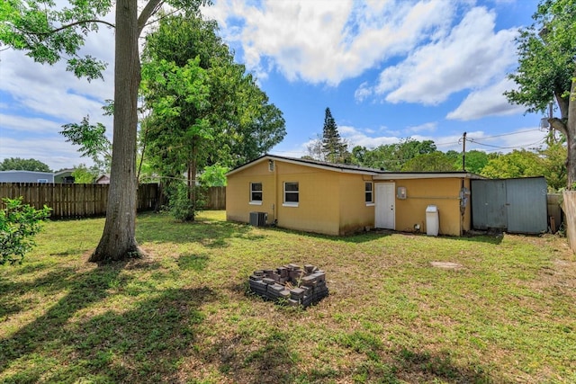 exterior space with an outbuilding, a fenced backyard, central AC unit, and a lawn