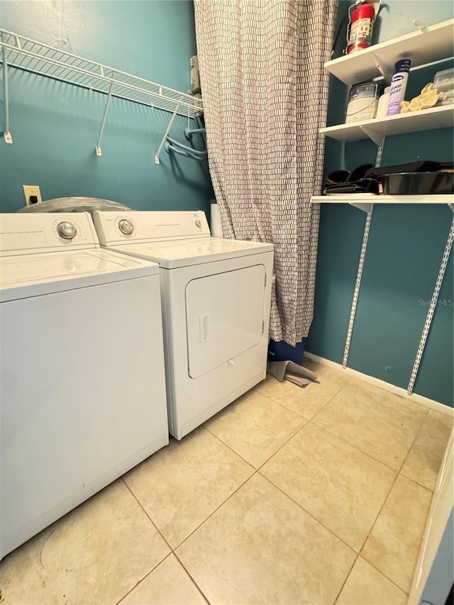 clothes washing area with independent washer and dryer, laundry area, and light tile patterned floors