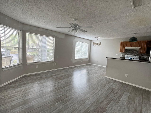 unfurnished living room featuring visible vents, baseboards, a textured ceiling, dark wood finished floors, and ceiling fan with notable chandelier
