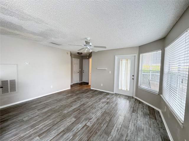 spare room featuring ceiling fan, a textured ceiling, visible vents, baseboards, and dark wood-style floors