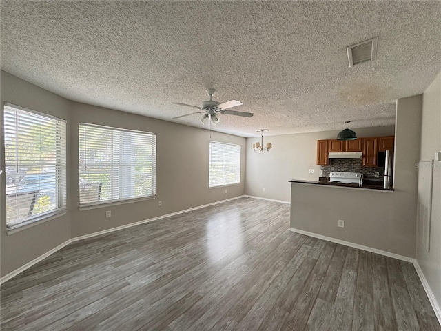 unfurnished living room with visible vents, dark wood-style flooring, baseboards, a textured ceiling, and ceiling fan with notable chandelier