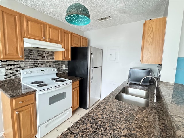 kitchen with visible vents, freestanding refrigerator, under cabinet range hood, a sink, and white electric stove