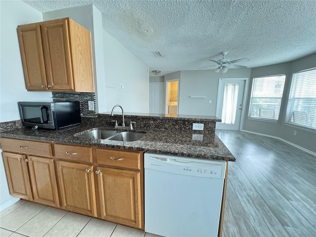 kitchen featuring ceiling fan, white dishwasher, a sink, stainless steel microwave, and a peninsula