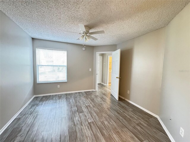 empty room featuring baseboards, a textured ceiling, ceiling fan, and dark wood-style floors
