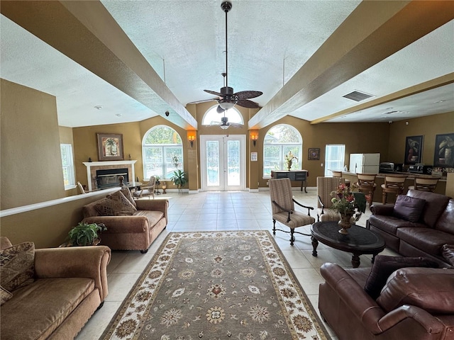 living room featuring a textured ceiling, a glass covered fireplace, light tile patterned floors, and visible vents