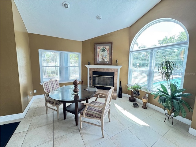 dining room with light tile patterned floors, plenty of natural light, and a tiled fireplace