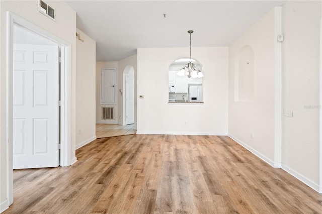2484 San Tecla St Unit 106, Orlando, FL 32835 - unfurnished dining area featuring light wood-style flooring, arched walkways, an inviting chandelier, and visible vents