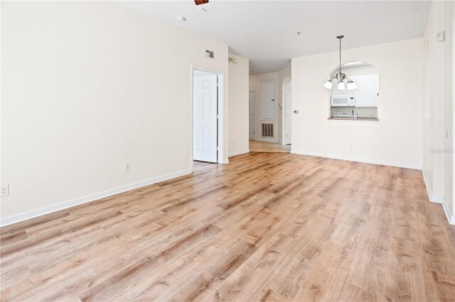 2484 San Tecla St Unit 106, Orlando, FL 32835 - unfurnished living room featuring light wood-type flooring, baseboards, visible vents, and arched walkways