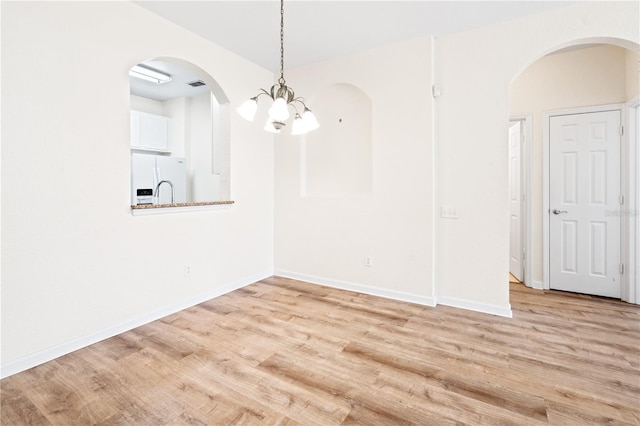 2484 San Tecla St Unit 106, Orlando, FL 32835 - unfurnished dining area featuring arched walkways, light wood finished floors, a notable chandelier, and baseboards