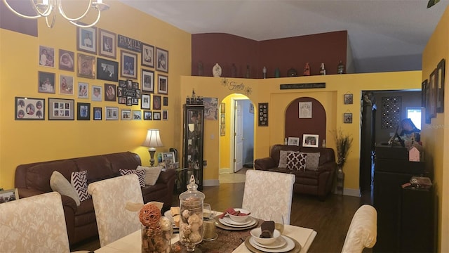 dining area featuring baseboards, arched walkways, a chandelier, and wood finished floors