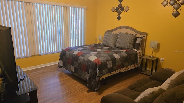bedroom with multiple windows, baseboards, and wood finished floors