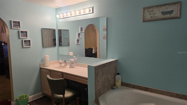 bathroom with vanity, a textured wall, and a garden tub