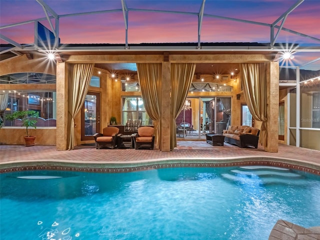 outdoor pool with a patio area, glass enclosure, and an outdoor hangout area
