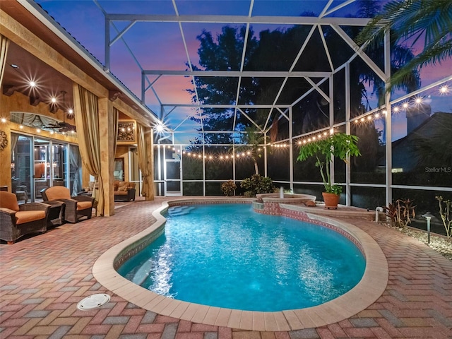 outdoor pool with a patio area, an in ground hot tub, and glass enclosure