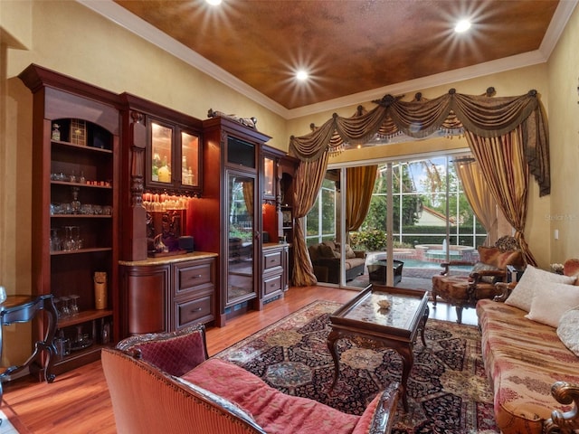 sitting room featuring crown molding, light wood-style flooring, recessed lighting, and a dry bar
