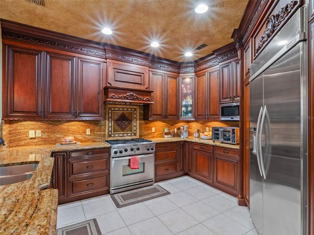 kitchen featuring visible vents, a sink, appliances with stainless steel finishes, backsplash, and light stone counters