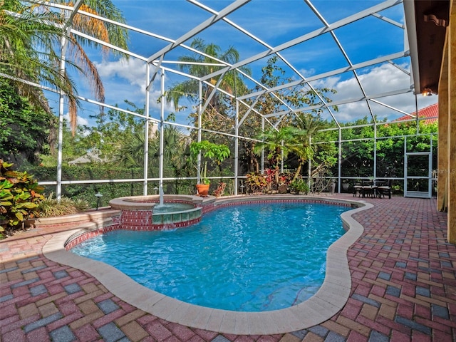 view of swimming pool featuring a pool with connected hot tub, a patio, and a lanai