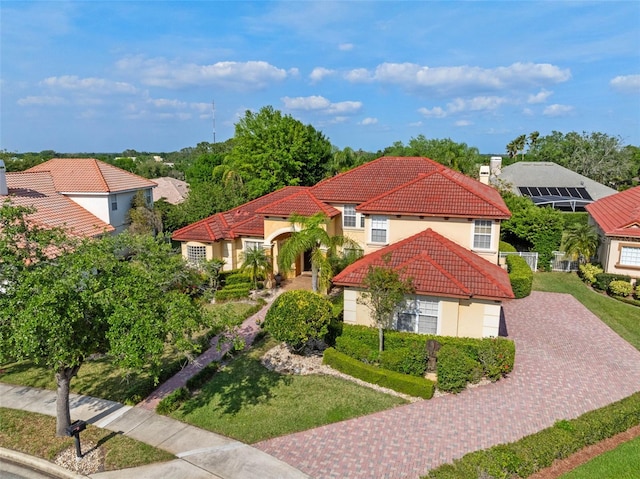 mediterranean / spanish home featuring decorative driveway, stucco siding, a chimney, and a tile roof