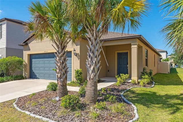 view of front of home with a front yard, stucco siding, a garage, and driveway