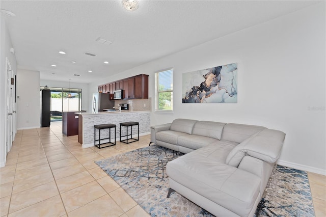 living area featuring light tile patterned floors, baseboards, and recessed lighting
