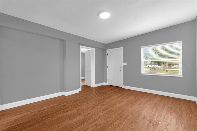 unfurnished room with baseboards and wood finished floors