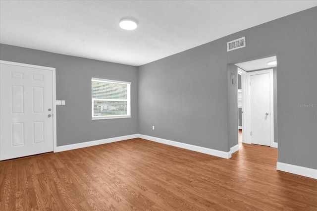 empty room with wood finished floors, baseboards, and visible vents