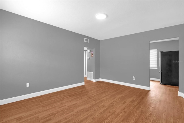 spare room with light wood-style flooring, baseboards, and visible vents