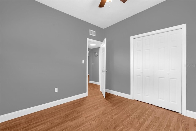 unfurnished bedroom featuring visible vents, baseboards, a closet, a ceiling fan, and wood finished floors