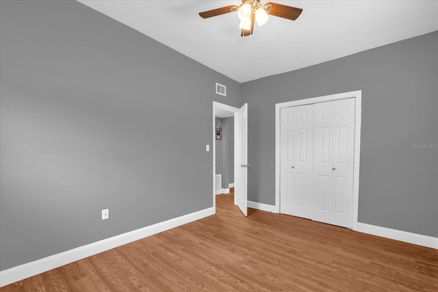 unfurnished bedroom with light wood-style flooring, a closet, baseboards, and visible vents