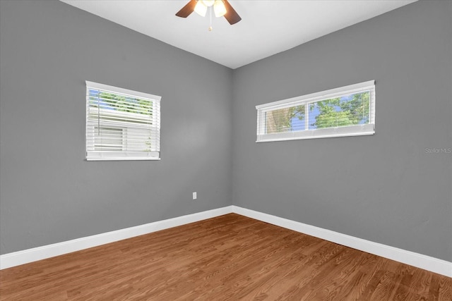 empty room with wood finished floors, baseboards, and a ceiling fan