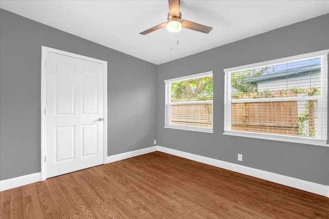 empty room with baseboards, ceiling fan, and wood finished floors