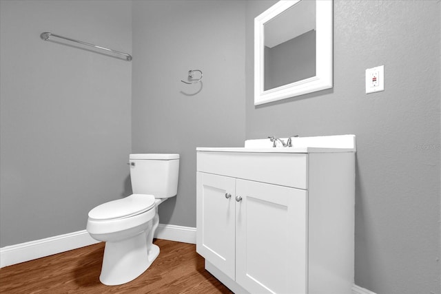 half bath with vanity, baseboards, toilet, and wood finished floors