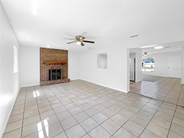 unfurnished living room featuring ceiling fan, a fireplace, light tile patterned floors, visible vents, and baseboards