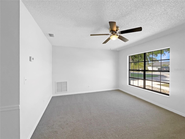 carpeted empty room with a textured ceiling, ceiling fan, baseboards, and visible vents