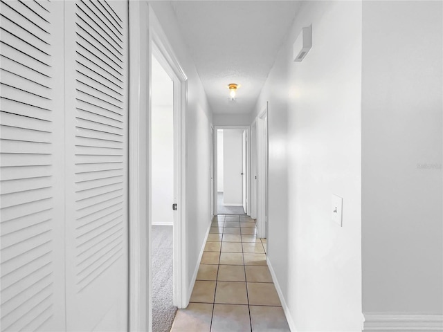 hallway with light tile patterned flooring and baseboards