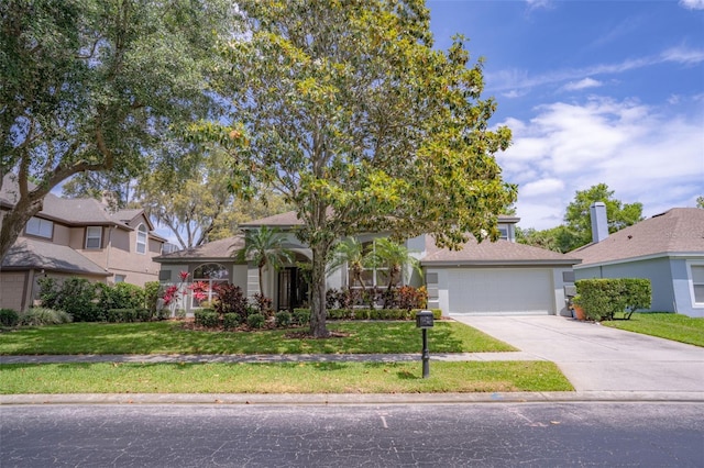 view of property hidden behind natural elements featuring a front lawn, driveway, and an attached garage