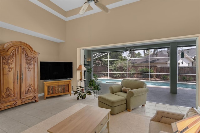 living area featuring light tile patterned floors, a sunroom, a ceiling fan, and a towering ceiling
