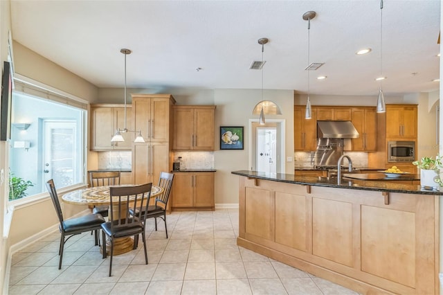 kitchen with stainless steel microwave, tasteful backsplash, under cabinet range hood, and baseboards